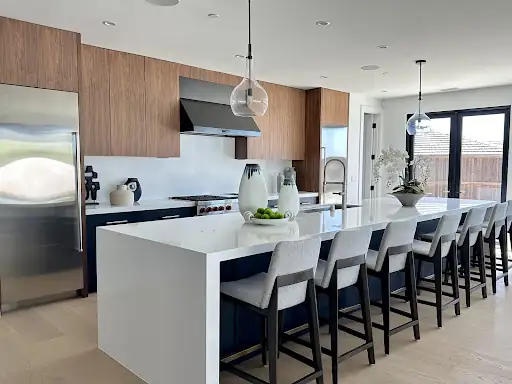 Dana Point kitchen remodel with white waterfall island, upholstered counter stools and wood-grain upper cabinets