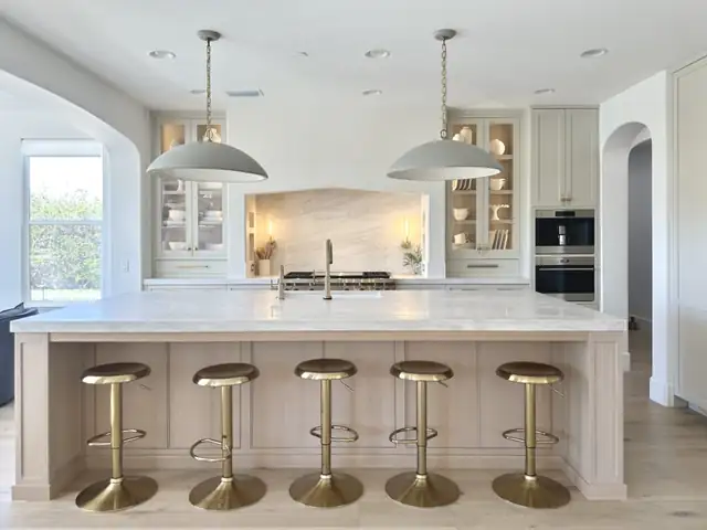 Coto de Caza kitchen remodel with cream custom cabinets, long island with brass counter stools and two large pendant lights