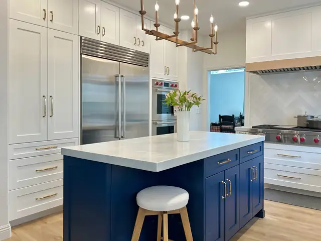 Santa Ana kitchen remodel with navy custom island, white quartz top, white shaker perimeter cabinets and brass chandelier