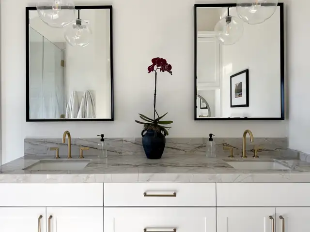 San Clemente bathroom remodel with white double vanity, gray marble counter, brass faucets and black framed mirrors