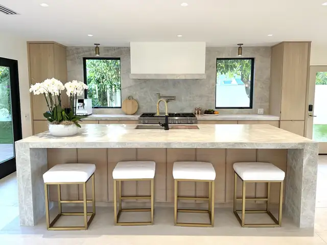 Orange County kitchen with white oak cabinets, quartzite waterfall island and white counter stools with brass bases